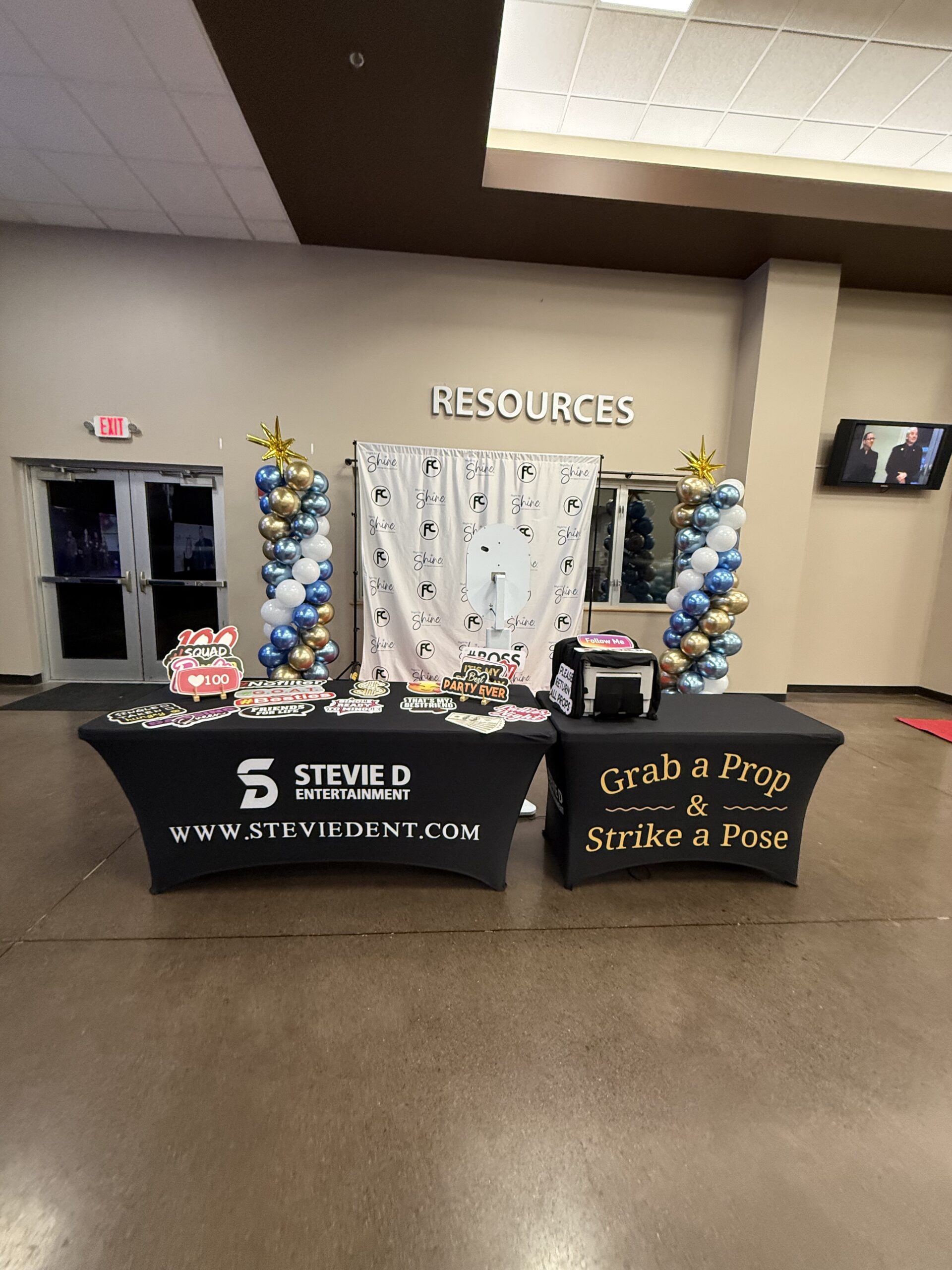 Full photo booth setup with branded tables and balloon columns at event venue